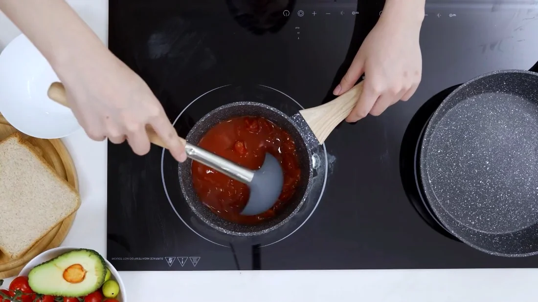 Silicone and wood keep the coating unscratched; the sauce does not care either way.