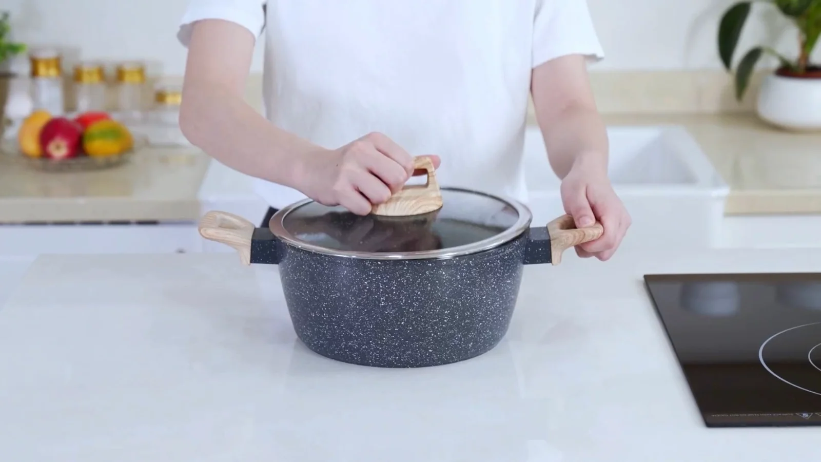 Hands placing a glass lid on a SODAY granite casserole