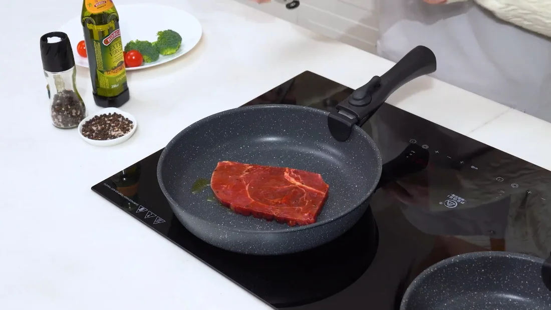 A steak on the detachable-handle skillet, pepper mill standing by.